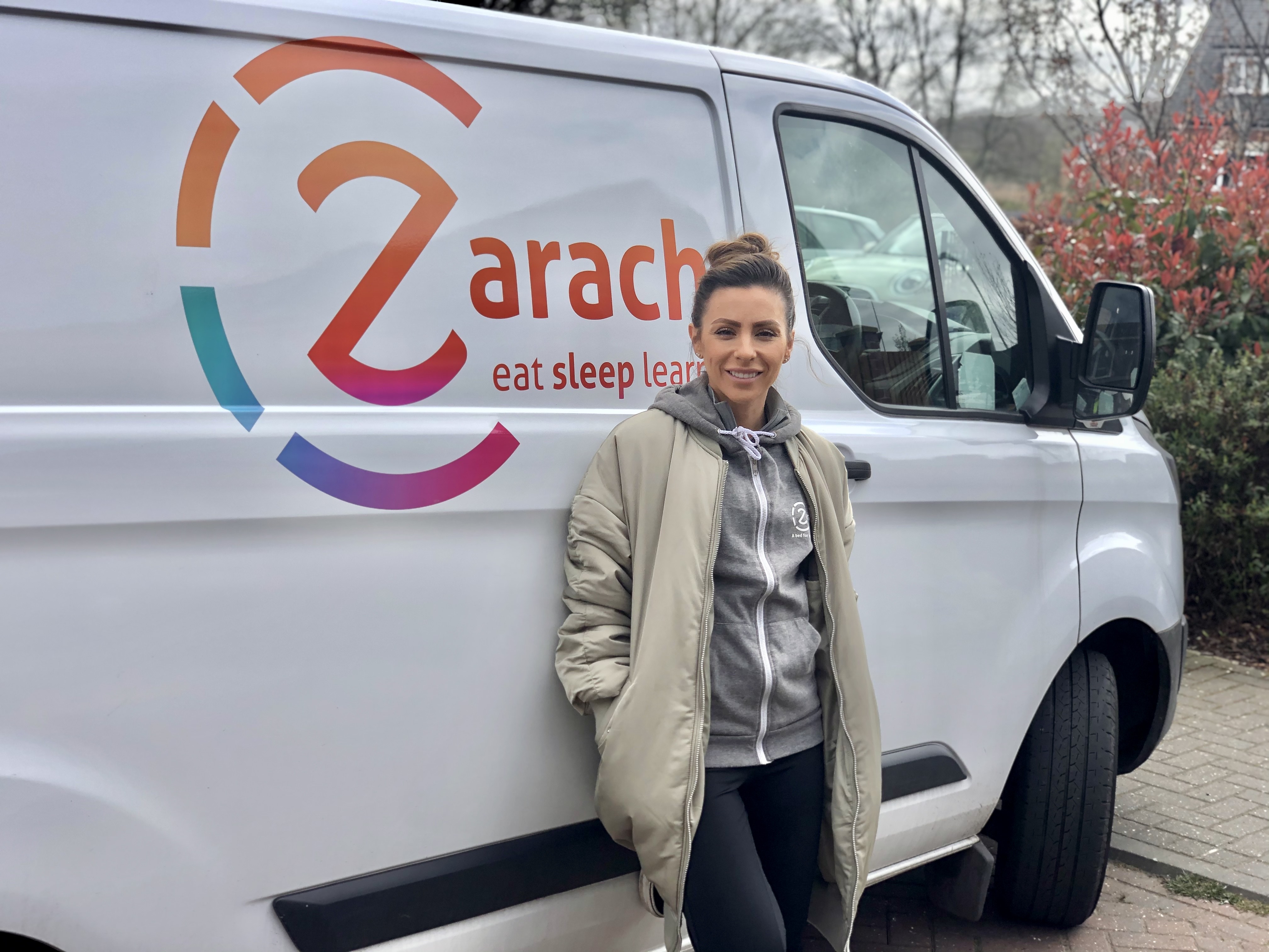 A person stood smiling in front of a Zarach-branded van